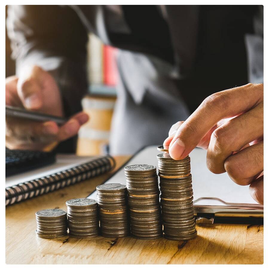 hand stacking coins on desk with calculator